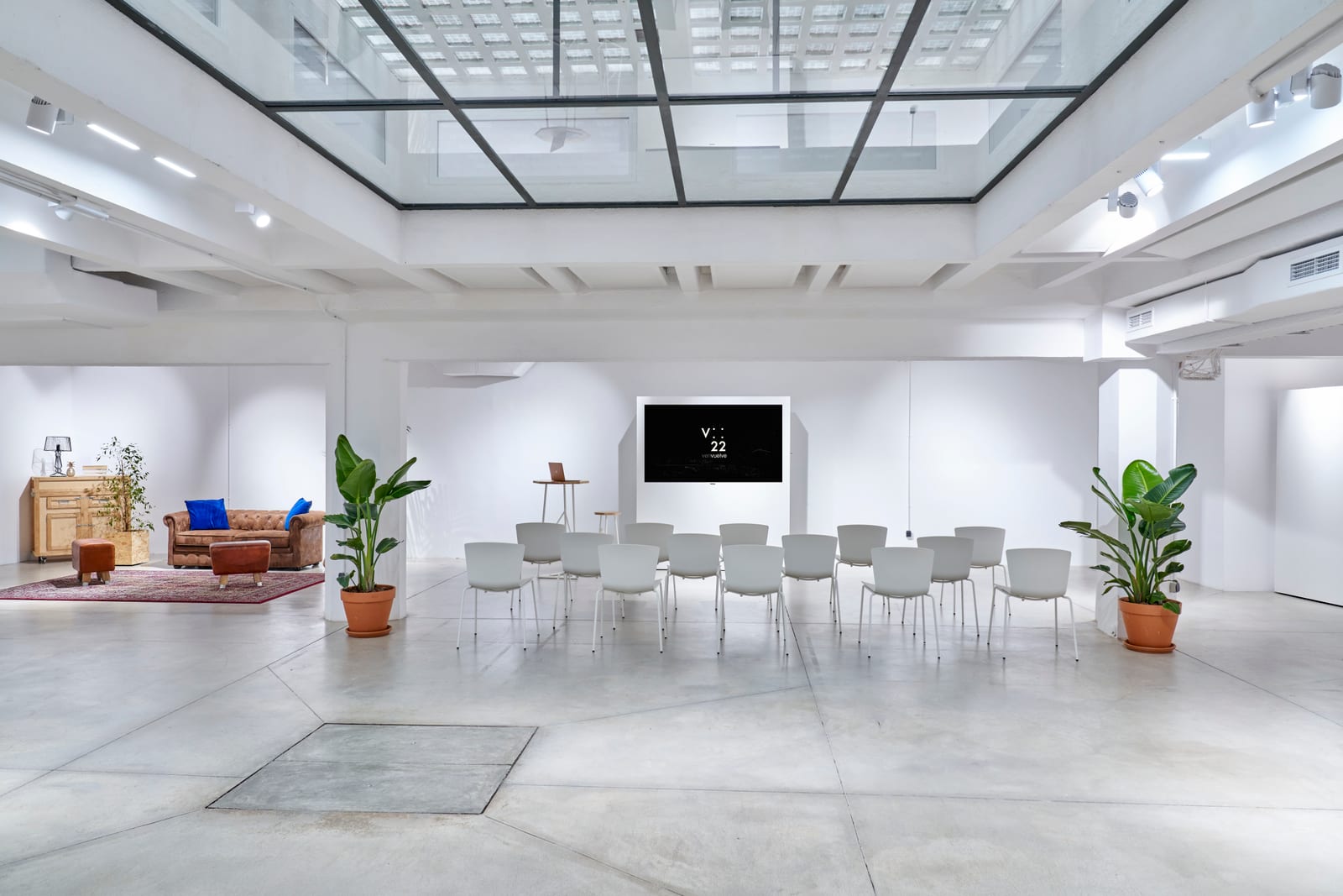 Sala de V22 montada en formato charla, con sillas en semicírculo frente a la pantalla